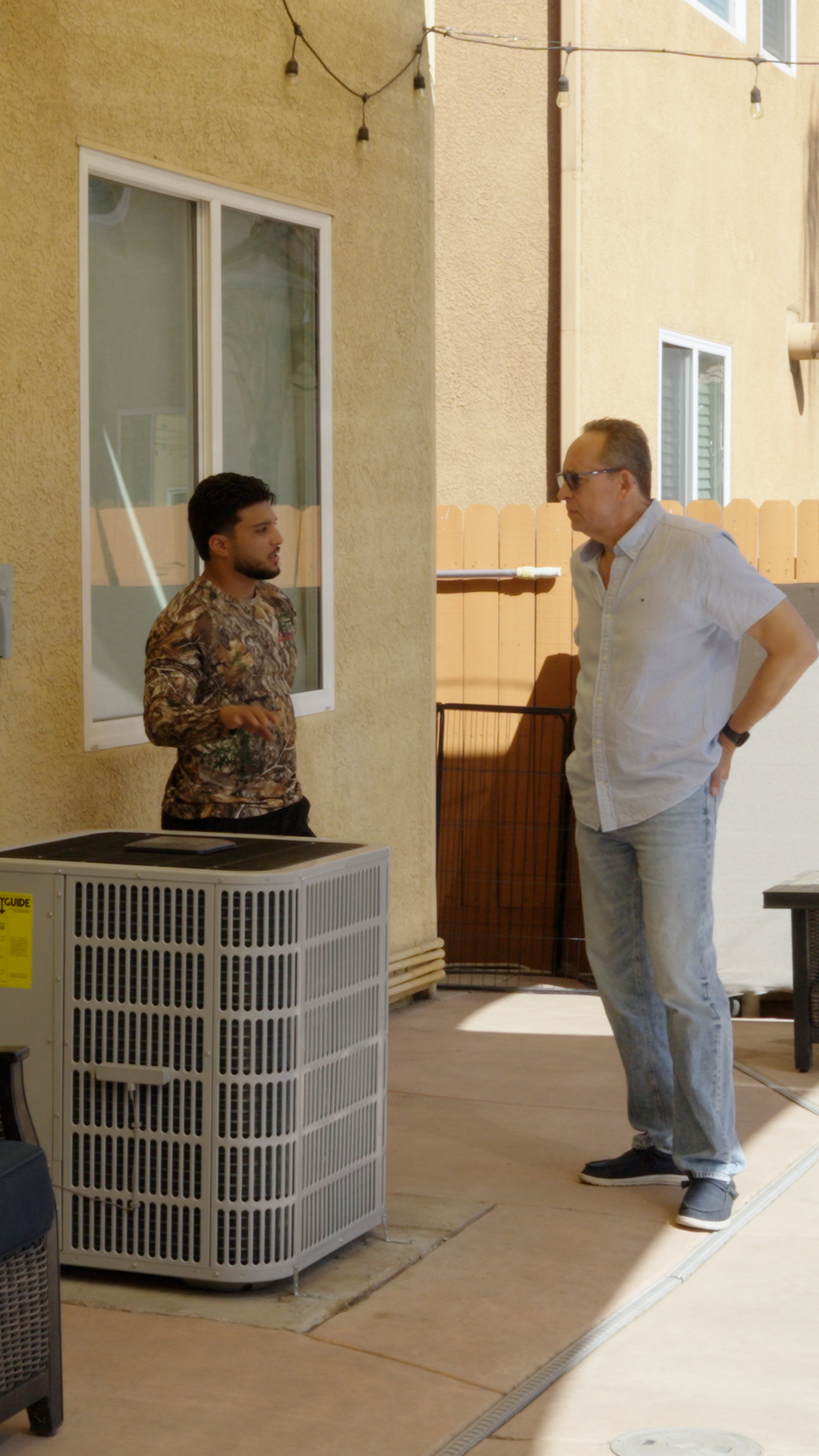 Alpha technician Enrique speaking with a customer beside an HVAC system