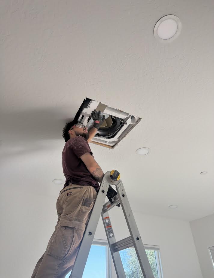 Technician installing a ceiling HVAC cassette